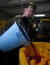 US_Navy_090316-N-6597H-004_Boatswains_Mate_2nd_Class_George_Cabeen_empties_used_hydraulic_fluid_into_a_storage_container